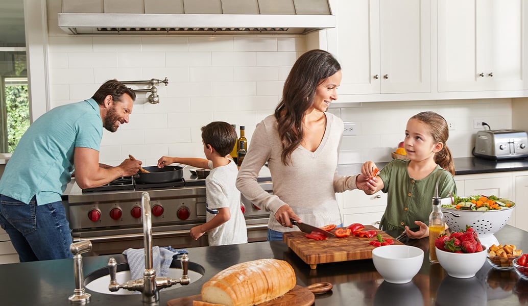 A family cooks together in the kitchen.