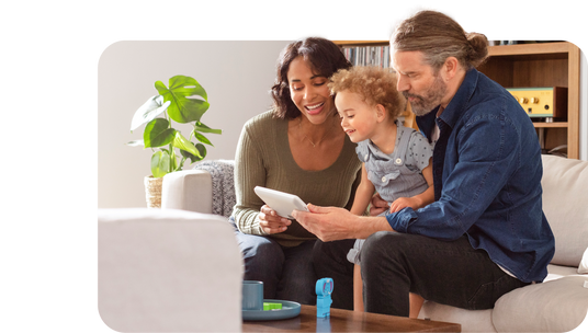 A man, woman, and child on a couch looking at a mobile device.